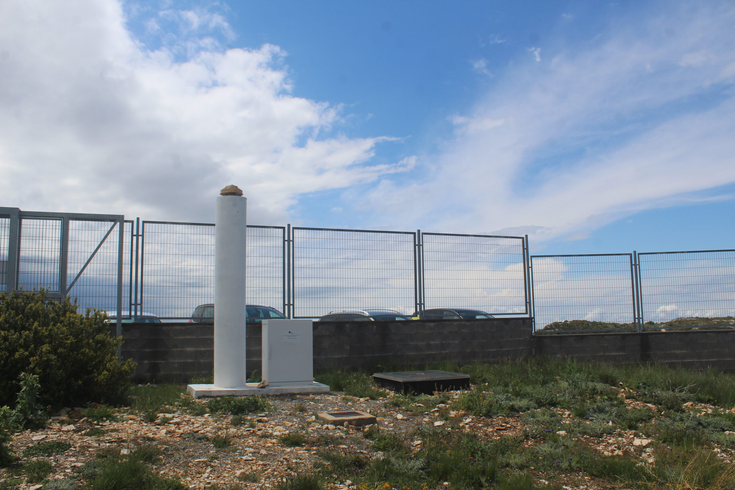 An all-sky camera atop a white cylindrical column beneath a partly cloudy sky at the Montsec observatory.