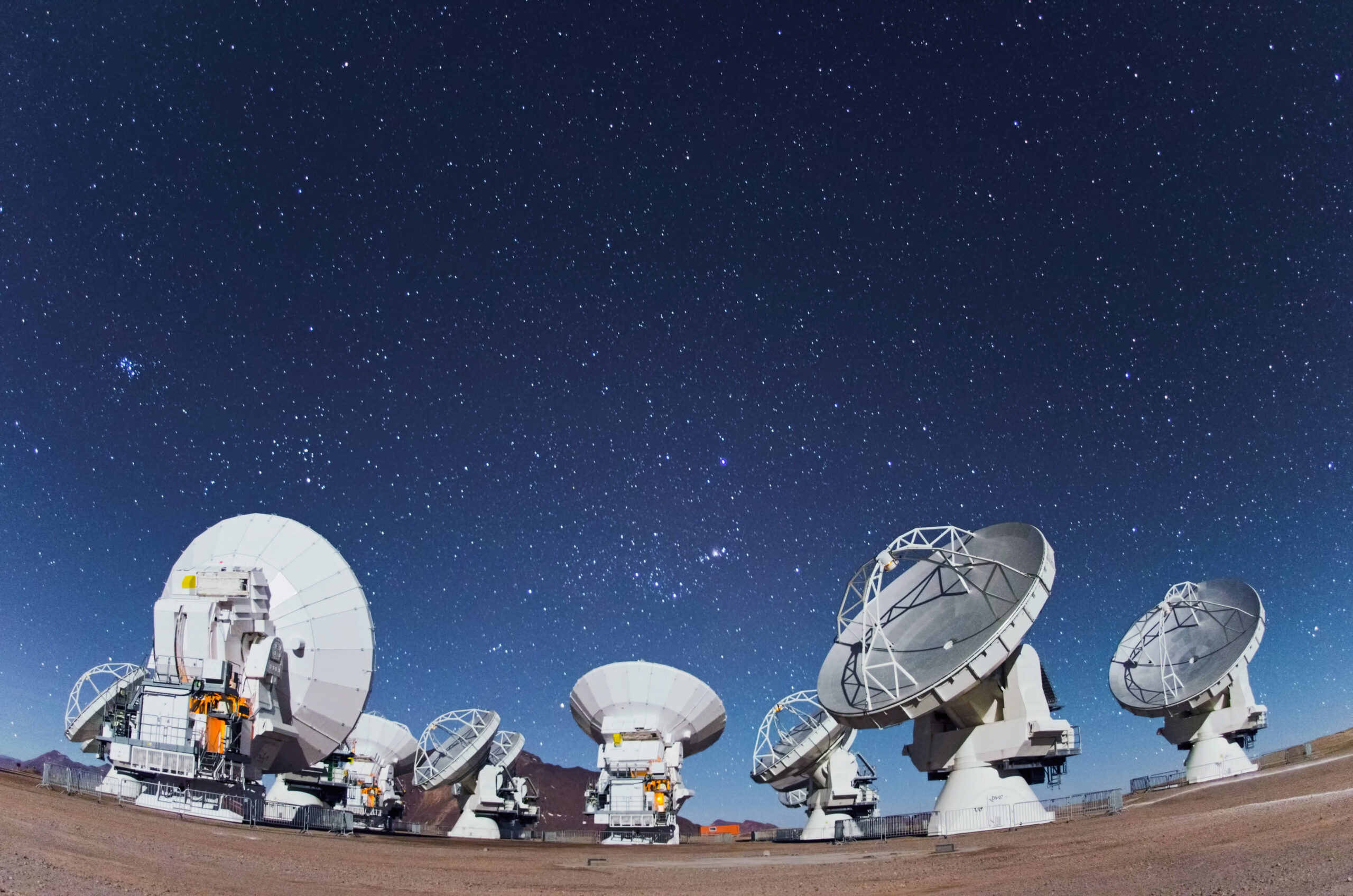 ALMA radio telescope dishes beneath a star-filled sky in the Chilean Andes.