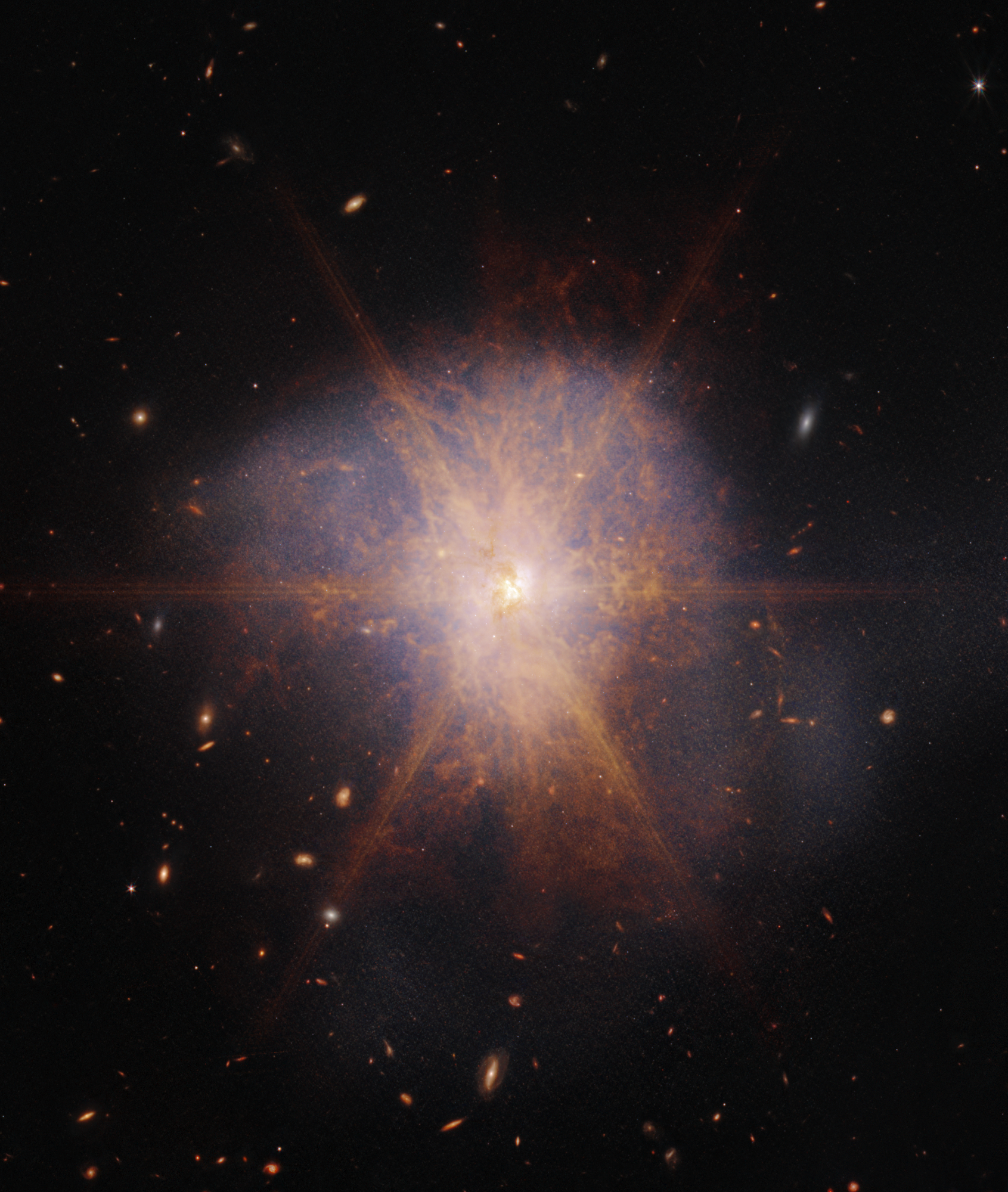 Archival Webb infrared image of the merging galaxy system Arp 220, with a bright orange center and faint blue outer structures.