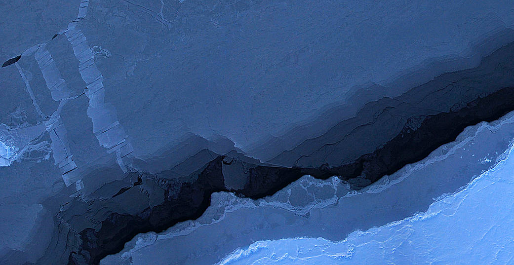 Blue sea ice surrounds a dark winding strip of open water in an aerial photographic mosaic.