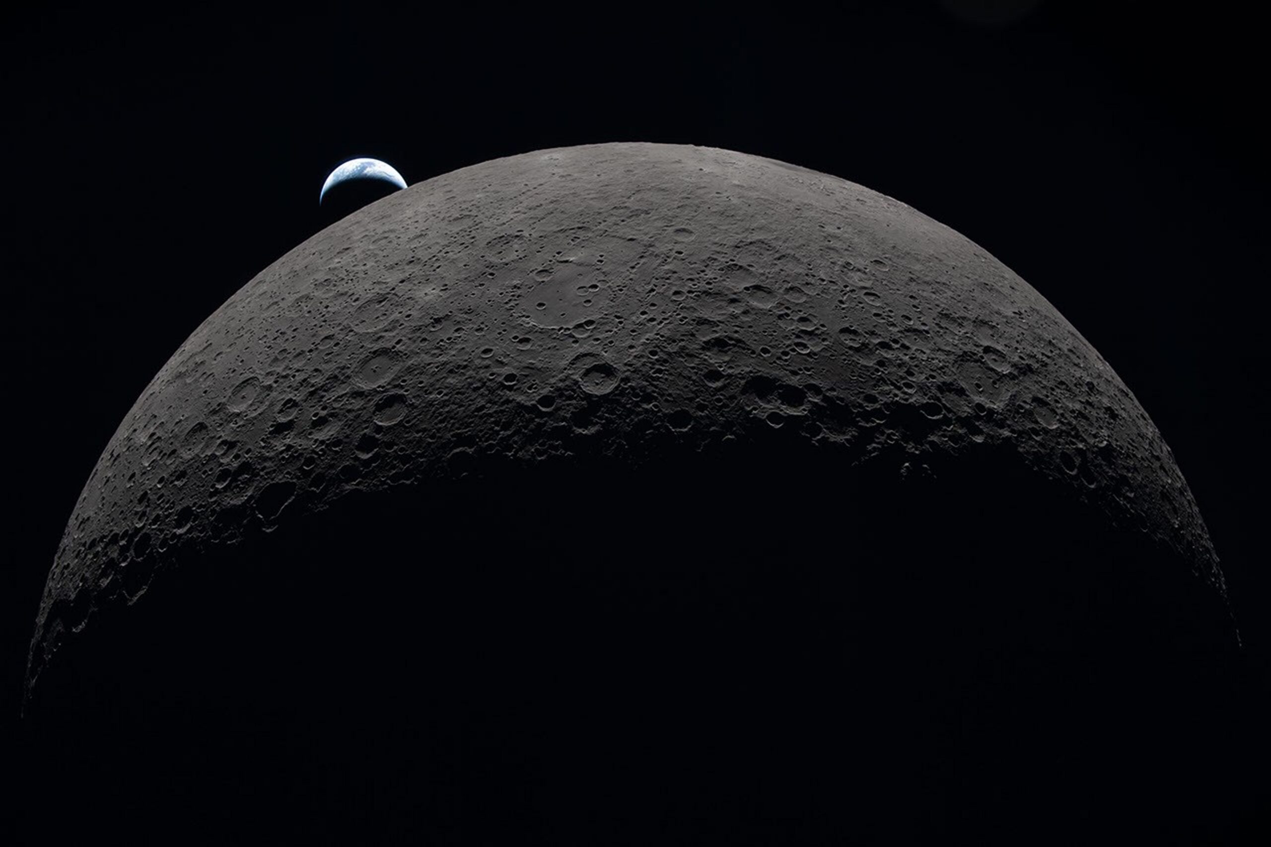 A crescent Earth sets behind the Moon’s heavily cratered surface in an Artemis II photograph.