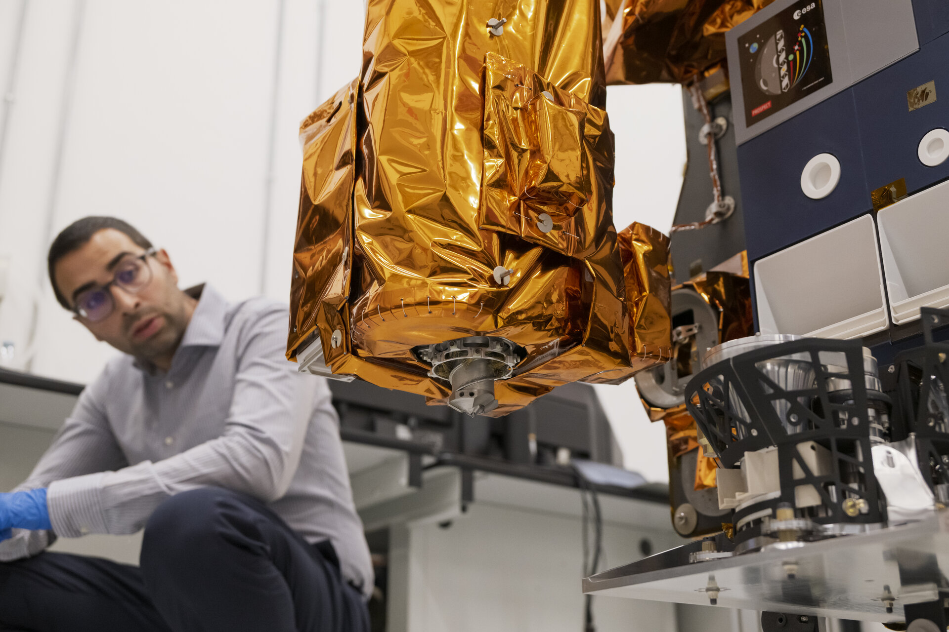 An engineer watches the Prospect lunar drill during ground testing.
