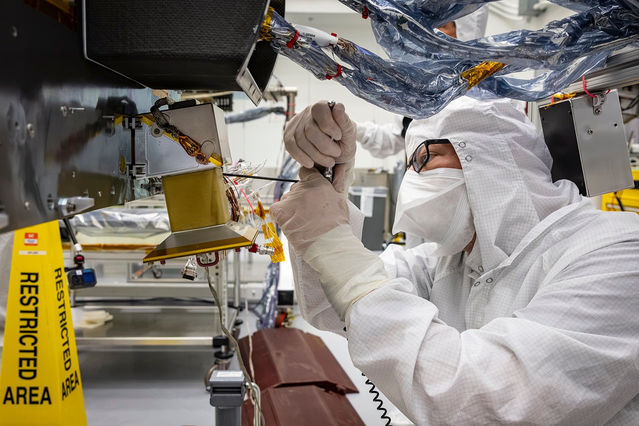 A cleanroom technician uses a hand tool beside Dragonfly’s navigation-camera hardware.