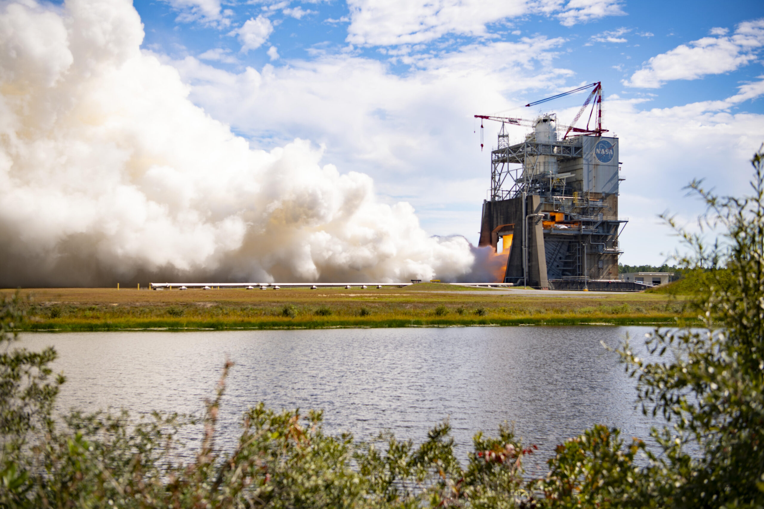 A large exhaust cloud spreads from the Fred Haise Test Stand during an RS-25 engine firing.