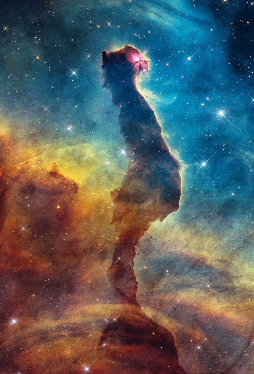 Hubble’s processed visible-light image of a dark dust pillar in the Cat’s Head Nebula, surrounded by glowing gas and stars.